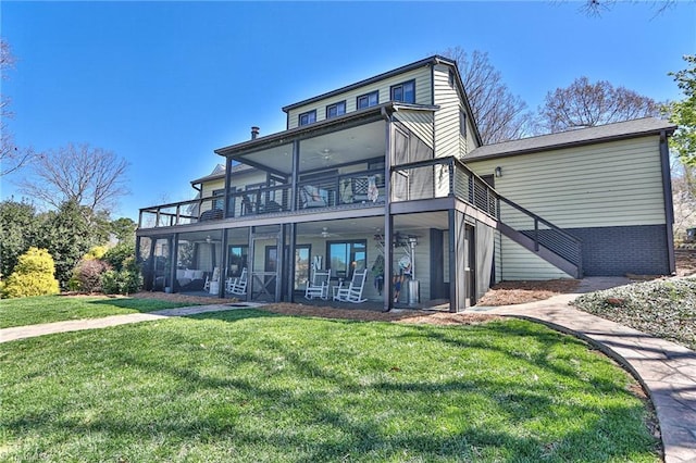 back of property featuring a sunroom, stairs, ceiling fan, a lawn, and a patio area