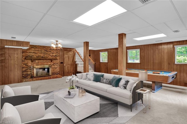 2665 Kecoughtan Rd, Pfafftown, NC 27040 - carpeted living area featuring wood walls, healthy amount of natural light, a chandelier, a drop ceiling, and a brick fireplace