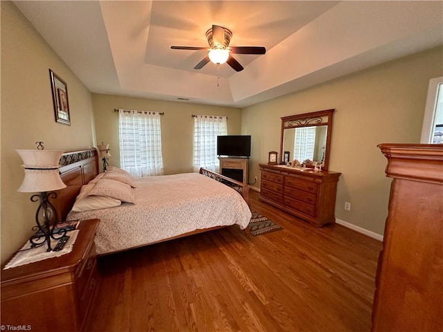 bedroom featuring hardwood / wood-style flooring, a raised ceiling, and ceiling fan