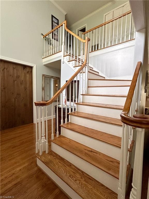 staircase featuring ornamental molding and hardwood / wood-style floors