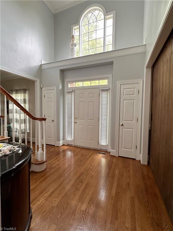 foyer featuring a high ceiling, crown molding, and wood-type flooring