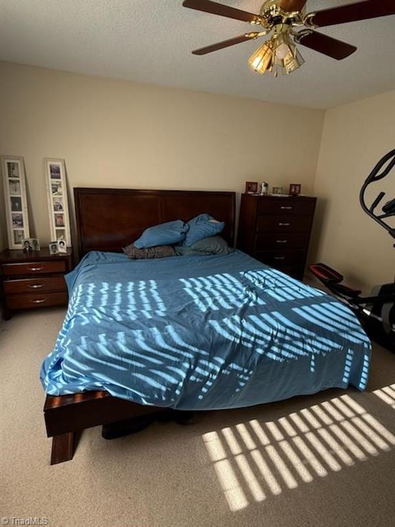 carpeted bedroom featuring ceiling fan and a textured ceiling