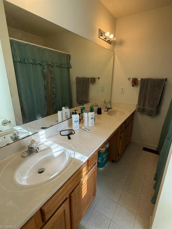 bathroom featuring vanity, tile patterned flooring, and a textured ceiling