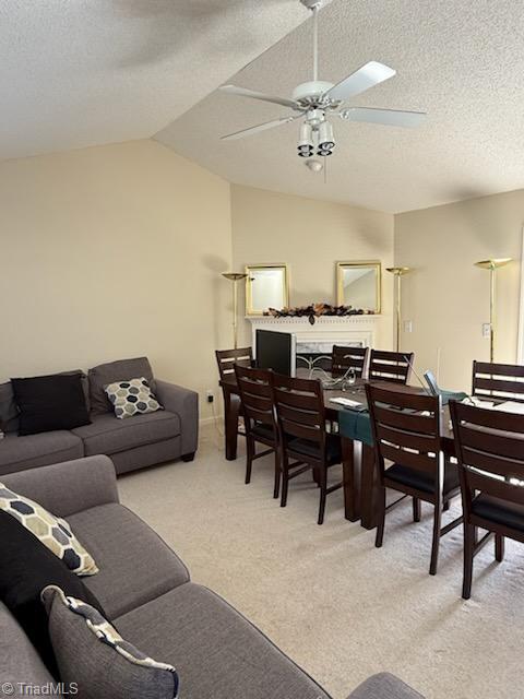 carpeted living room with ceiling fan, vaulted ceiling, and a textured ceiling