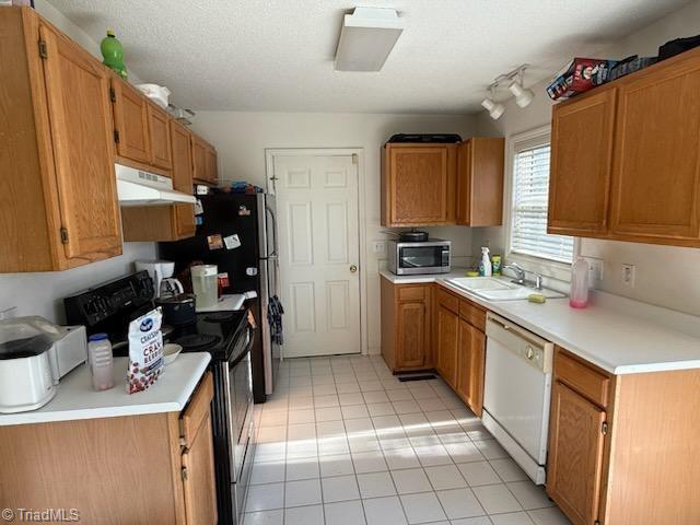 kitchen with dishwasher, sink, light tile patterned floors, a textured ceiling, and electric stove