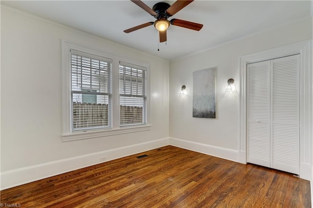 unfurnished bedroom featuring dark hardwood / wood-style floors, ceiling fan, ornamental molding, and a closet