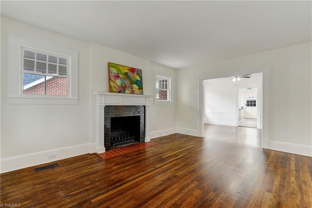 unfurnished living room featuring wood-type flooring, a brick fireplace, and ceiling fan