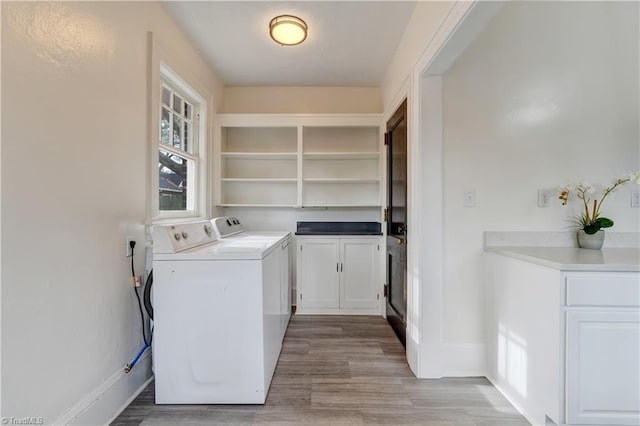 laundry area featuring washer and clothes dryer, cabinets, and light wood-type flooring