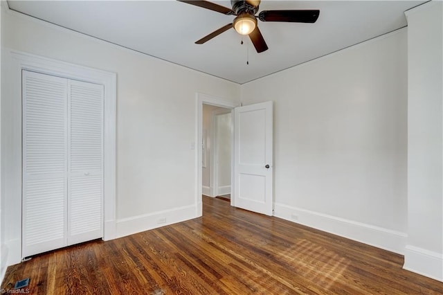 unfurnished bedroom with ceiling fan, dark wood-type flooring, and a closet