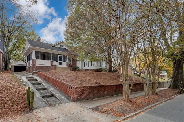 view of front of home with a sunroom, an outbuilding, and a garage