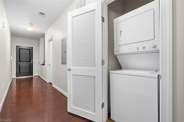 clothes washing area featuring stacked washer / dryer and dark wood-type flooring