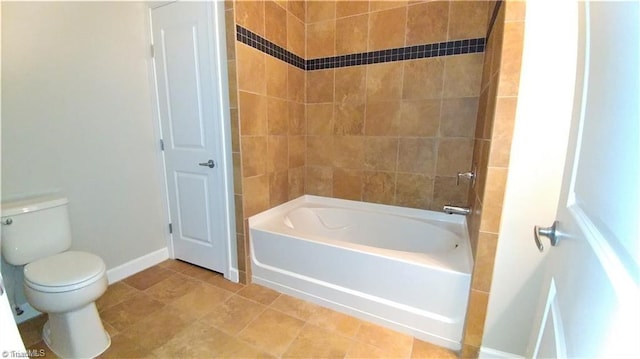 bathroom featuring tile floors, tiled shower / bath combo, and toilet