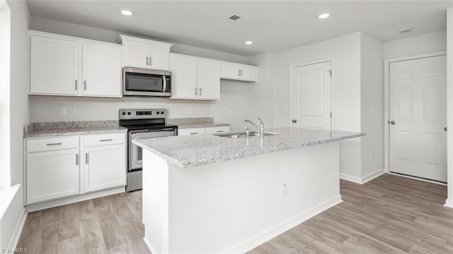 1529 String Dr, Winston-Salem, NC 27107 - kitchen featuring stainless steel appliances, a sink, white cabinetry, a kitchen island with sink, and light wood-style floors