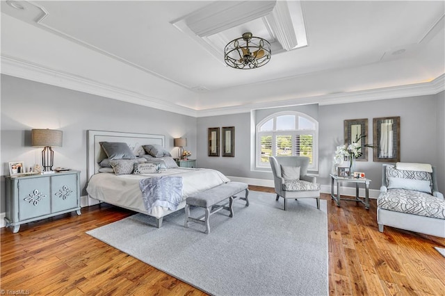 bedroom featuring a raised ceiling, baseboards, and wood finished floors