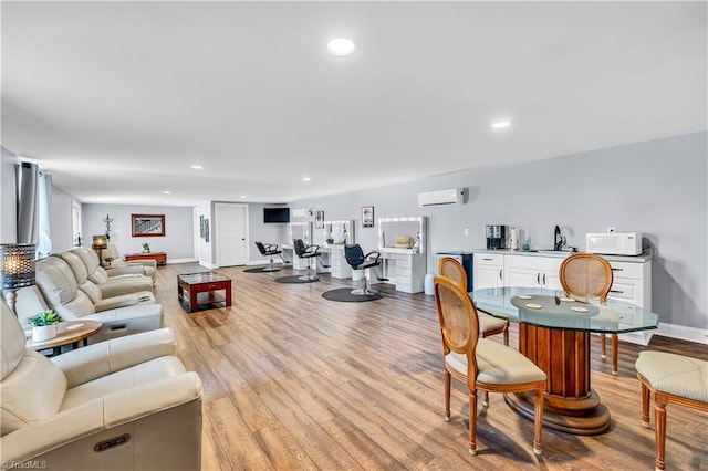 living area with light wood finished floors, recessed lighting, a wall mounted AC, and baseboards