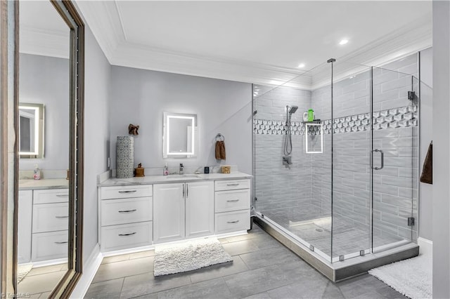 bathroom with vanity, a shower stall, crown molding, and baseboards