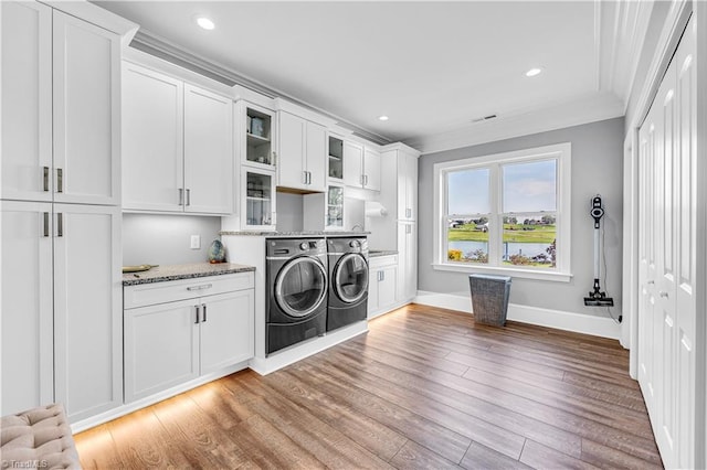 laundry room with light wood-type flooring, ornamental molding, washing machine and dryer, recessed lighting, and cabinet space