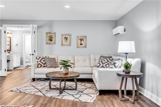 living room featuring recessed lighting, baseboards, an AC wall unit, and wood finished floors