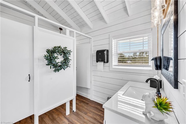 bathroom with wood ceiling, wood walls, vaulted ceiling with beams, and a sink