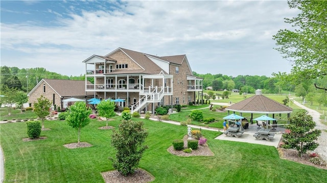 back of property featuring a balcony, stairs, a gazebo, a patio area, and a lawn