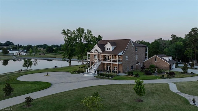 view of front of home featuring a front lawn, stairway, and a water view