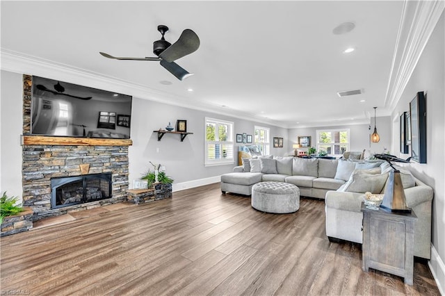 living room with visible vents, ornamental molding, wood finished floors, a fireplace, and baseboards