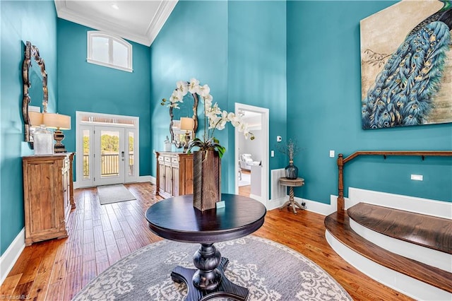 bathroom featuring baseboards, crown molding, a high ceiling, and wood finished floors