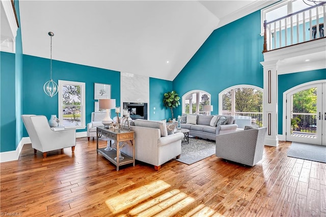 living area with high vaulted ceiling, baseboards, wood-type flooring, and a chandelier