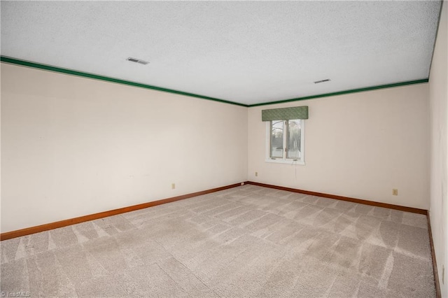 spare room with light carpet, ornamental molding, and a textured ceiling