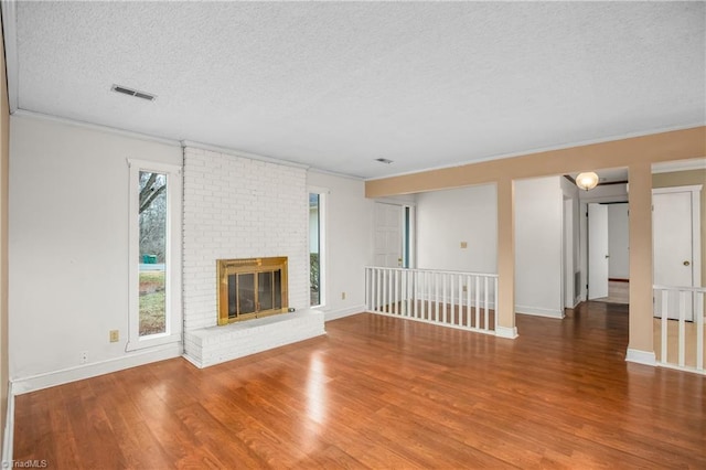 unfurnished living room featuring crown molding, wood-type flooring, a fireplace, and a textured ceiling