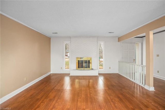 unfurnished living room with crown molding, wood-type flooring, and a brick fireplace