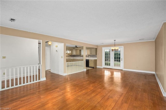 unfurnished living room with ceiling fan with notable chandelier, ornamental molding, and hardwood / wood-style floors