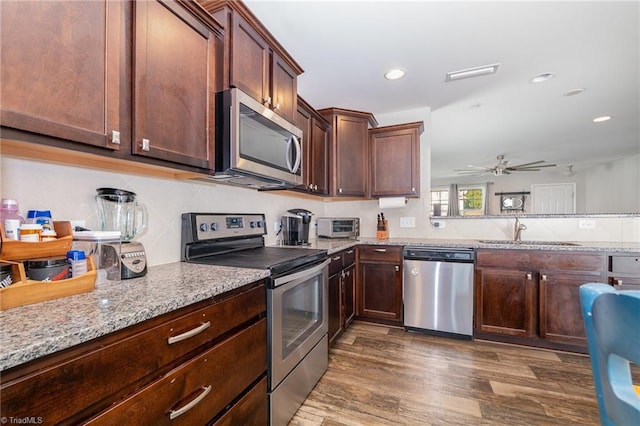 kitchen featuring dark wood-type flooring, sink, tasteful backsplash, light stone counters, and appliances with stainless steel finishes