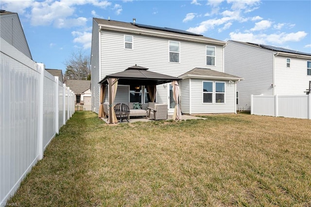 rear view of property with a yard, a gazebo, an outdoor hangout area, and solar panels