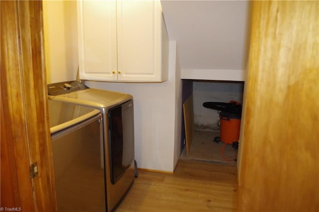 laundry room featuring cabinets, light wood-type flooring, and separate washer and dryer