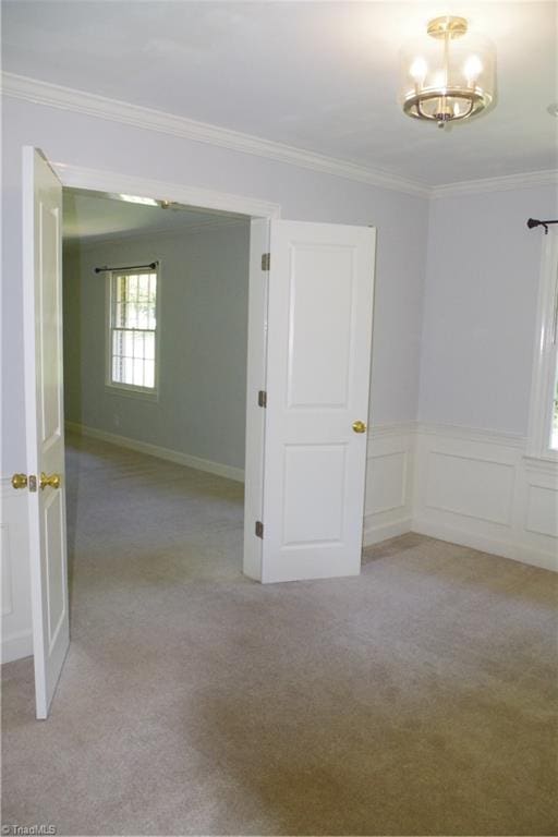 carpeted empty room featuring crown molding and a chandelier