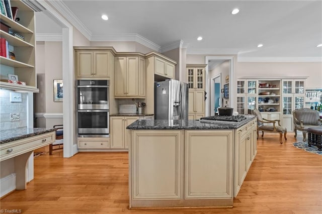 kitchen featuring light wood-type flooring, stainless steel appliances, dark stone counters, and cream cabinetry