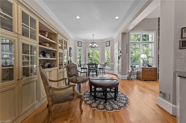 sitting room with ornamental molding, an inviting chandelier, and light hardwood / wood-style flooring