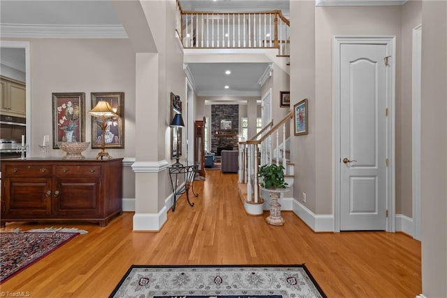 entryway featuring a stone fireplace, ornamental molding, and light hardwood / wood-style floors