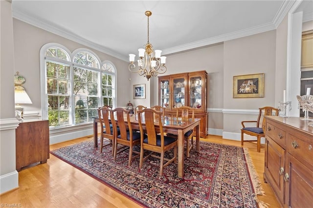 dining area with crown molding, a notable chandelier, and light hardwood / wood-style flooring