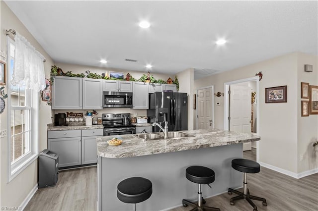 1595 Cheatham Ford Rd, Hiddenite, NC 28636 - kitchen with a breakfast bar area, appliances with stainless steel finishes, a sink, and light wood-style floors