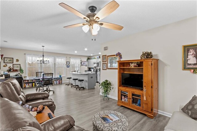 1595 Cheatham Ford Rd, Hiddenite, NC 28636 - living area featuring light wood-style floors, ceiling fan with notable chandelier, baseboards, and a textured ceiling