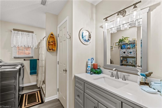 1595 Cheatham Ford Rd, Hiddenite, NC 28636 - bathroom featuring vanity, baseboards, visible vents, washer and dryer, and wood finished floors