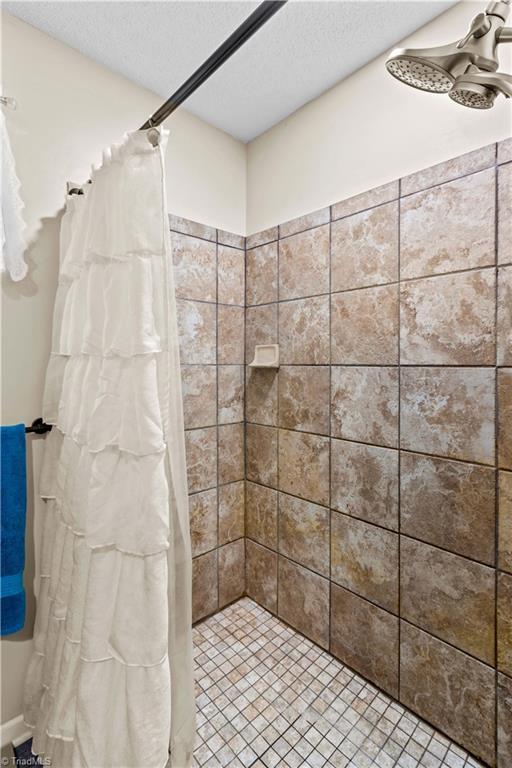 1595 Cheatham Ford Rd, Hiddenite, NC 28636 - bathroom featuring a textured ceiling and tiled shower