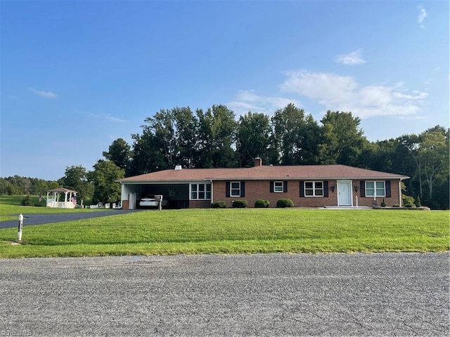 ranch-style home featuring driveway, a front lawn, a carport, and brick siding