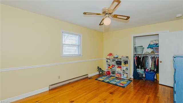 rec room with ceiling fan, dark wood-type flooring, and a baseboard heating unit