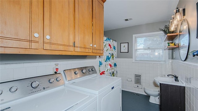 laundry area featuring washer and clothes dryer, sink, tile patterned flooring, tile walls, and heating unit