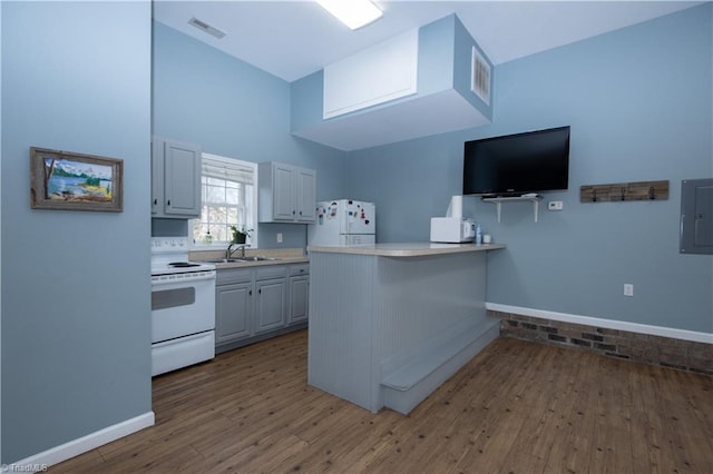 kitchen with white appliances, dark wood-type flooring, kitchen peninsula, a breakfast bar, and electric panel