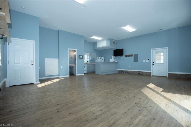 unfurnished living room with dark wood-type flooring, electric panel, and a towering ceiling