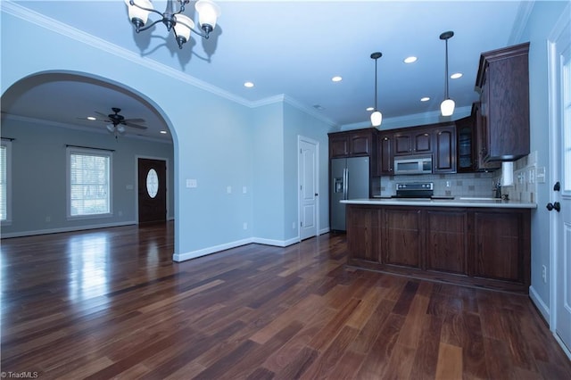 kitchen featuring appliances with stainless steel finishes, decorative backsplash, dark hardwood / wood-style floors, kitchen peninsula, and dark brown cabinets